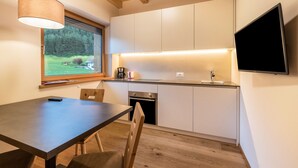 A modern kitchen with white cabinets, a built-in oven, and a large window overlooking a green landscape. - Apartment "Stefansdorf Wohnung 9" with Mountain View, Wi-Fi, Garden, Balcony, and Barbecue (St. Lorenzen)