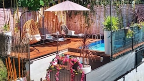 Une terrasse sur le toit dotée d’une piscine, de chaises longues et d’une arche décorative.