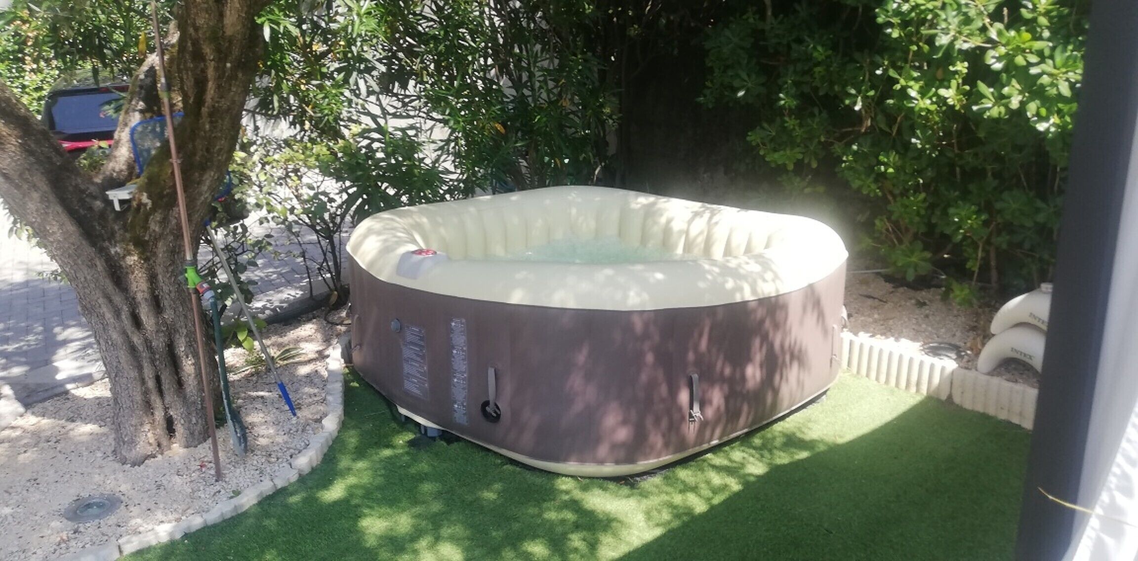 Un jacuzzi en un jardín con un árbol y una valla.