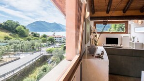Ein Balkon mit Blick auf einen See und Berge, inklusive Fernseher und einer Couch.