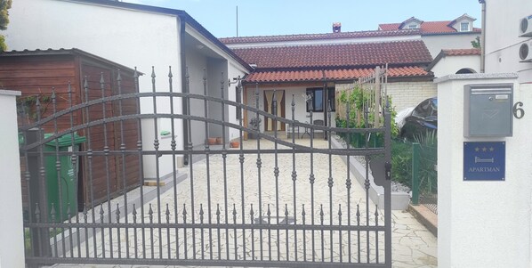 A gated entrance to a residential building with a tiled roof and a mailbox labeled '6'. - House with beautiful garden (Fažana)