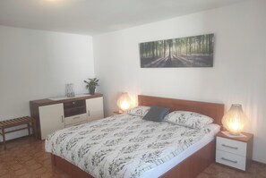 A bedroom with a bed, bedside tables, a desk, and a wall-mounted painting. - House with beautiful garden (Fažana)