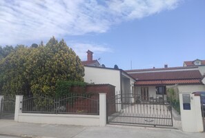 A residential property with a gated entrance, a red-tiled roof, and a large tree in front. - House with beautiful garden (Fažana)