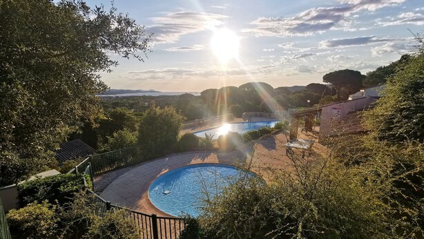 Un espace piscine doté d’une piscine circulaire, entourée d’arbres et offrant une vue sur le paysage.