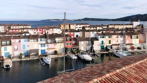 Une ville côtière aux bâtiments aux couleurs vives, un port de plaisance rempli de bateaux et une vue dégagée sur la mer.