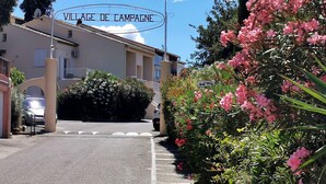 Un bâtiment sur lequel est apposée une enseigne indiquant « VILLAGE DE CAMPAGNE », ainsi qu’une zone de stationnement avec une signalétique indiquant la présence d’un service de lavage automobile.