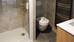 A modern bathroom with a glass-enclosed shower, a toilet, and a wooden vanity. - Appartement 2 Pieces Pied DES Pistes Proche Centre Balnéo et Randonnées (Aragnouet)