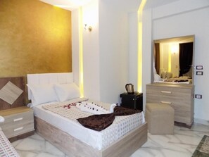 A modern bedroom with a bed, bedside tables, a dresser, and a mirror. - City Hotel (Cairo)