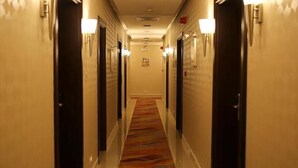 Un couloir d'hôtel avec un revêtement de sol en moquette, des portes des deux côtés et des luminaires fixés au mur.