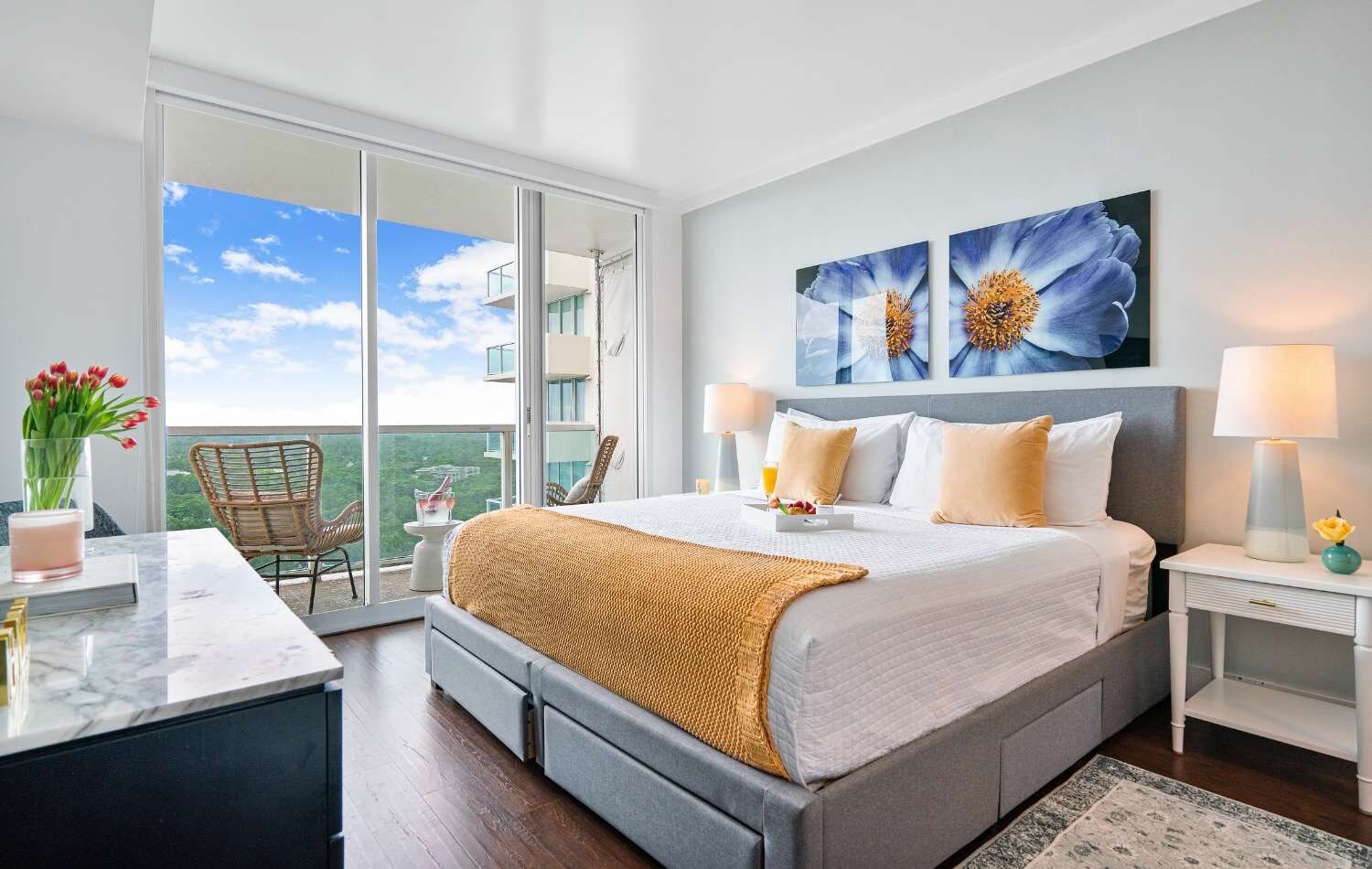 Habitación de hotel con una cama grande, un balcón con vistas y obras de arte en la pared.