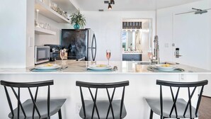 A modern kitchen with a central island, black chairs, and a dining table set for two.