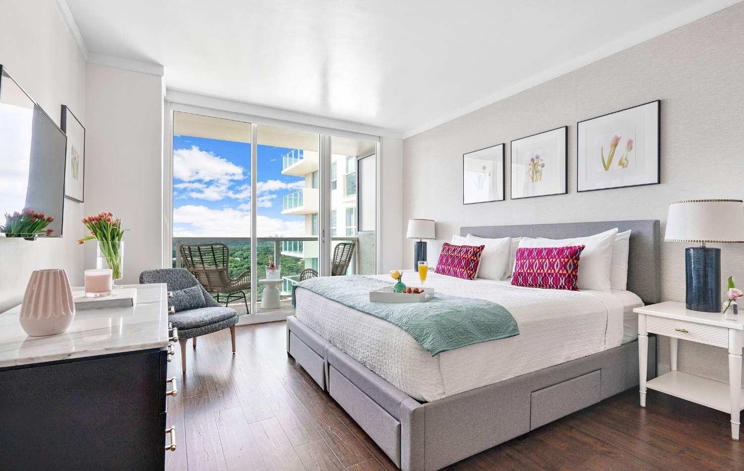 Ein modernes Hotelzimmer mit einem großen Bett, einem Schreibtisch, einem Sessel und einem Balkon mit Blick auf die Stadt.