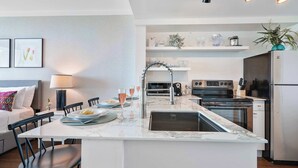 A modern kitchen with a central island, built-in appliances, and a dining area with a table and chairs.