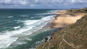 Een kustlandschap met een zandstrand en rotskliffen.