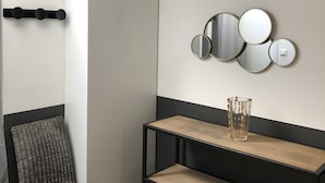 Een moderne kamer met een zwart-wit kleurenschema, met een zwarte stoel, een houten console tafel en een wandmontage van spiegels.