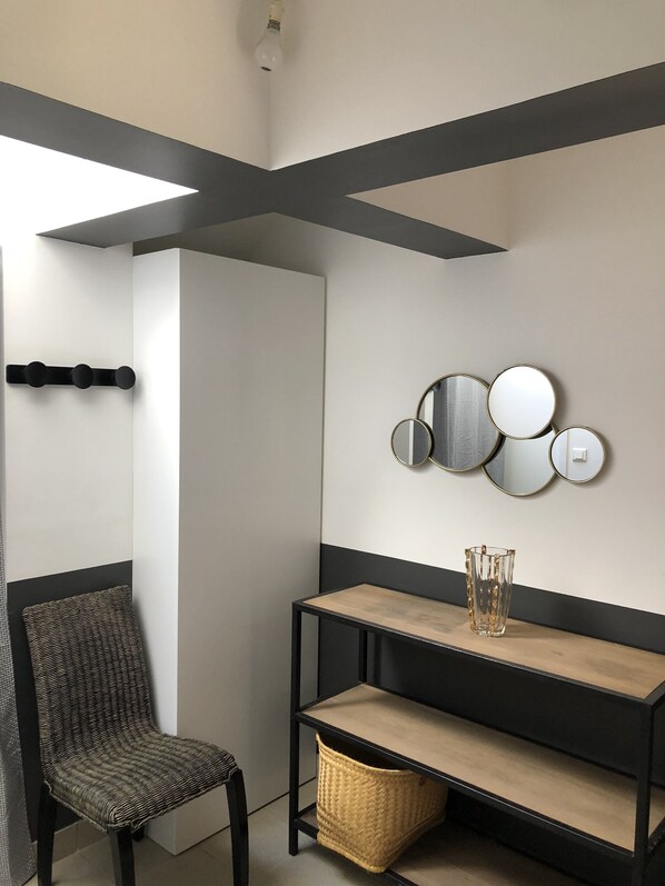A modern room with a black and white color scheme, featuring a black chair, a wooden console table, and a wall-mounted mirror arrangement. - Pointe de Mousterlin: Direct access to the beach (Fouesnant)