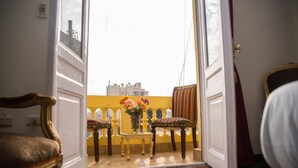 An open door leading to a balcony with a yellow wall, a table with flowers, and two chairs. - Grand Talat Harb Plaza (Cairo)
