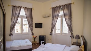 A hotel room with two beds, a TV, an air conditioner, and a small table with a lamp. - Grand Talat Harb Plaza (Cairo)