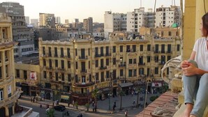 A person sitting on a rooftop with a view of a cityscape. - Grand Talat Harb Plaza (Cairo)