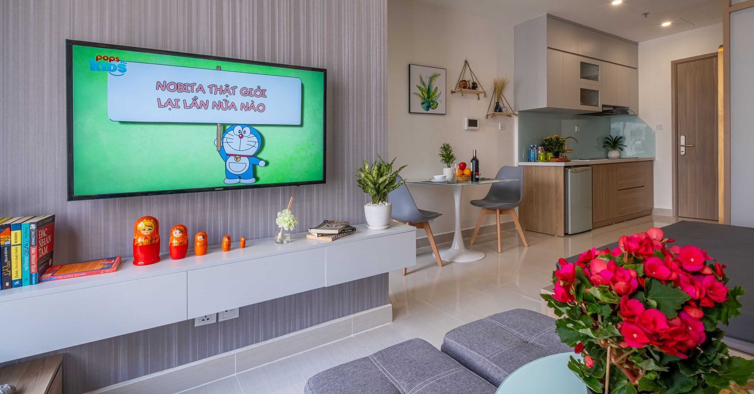 Ein modernes Wohnzimmer mit Flachbildfernseher, einer Couch, einem Couchtisch und einem Essbereich mit Stühlen.
