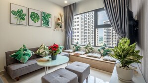 A modern living room with a sofa, ottomans, a coffee table, and a large window with curtains. - Bom Homes- Vinhomes Ocean Park  (Hanoi)