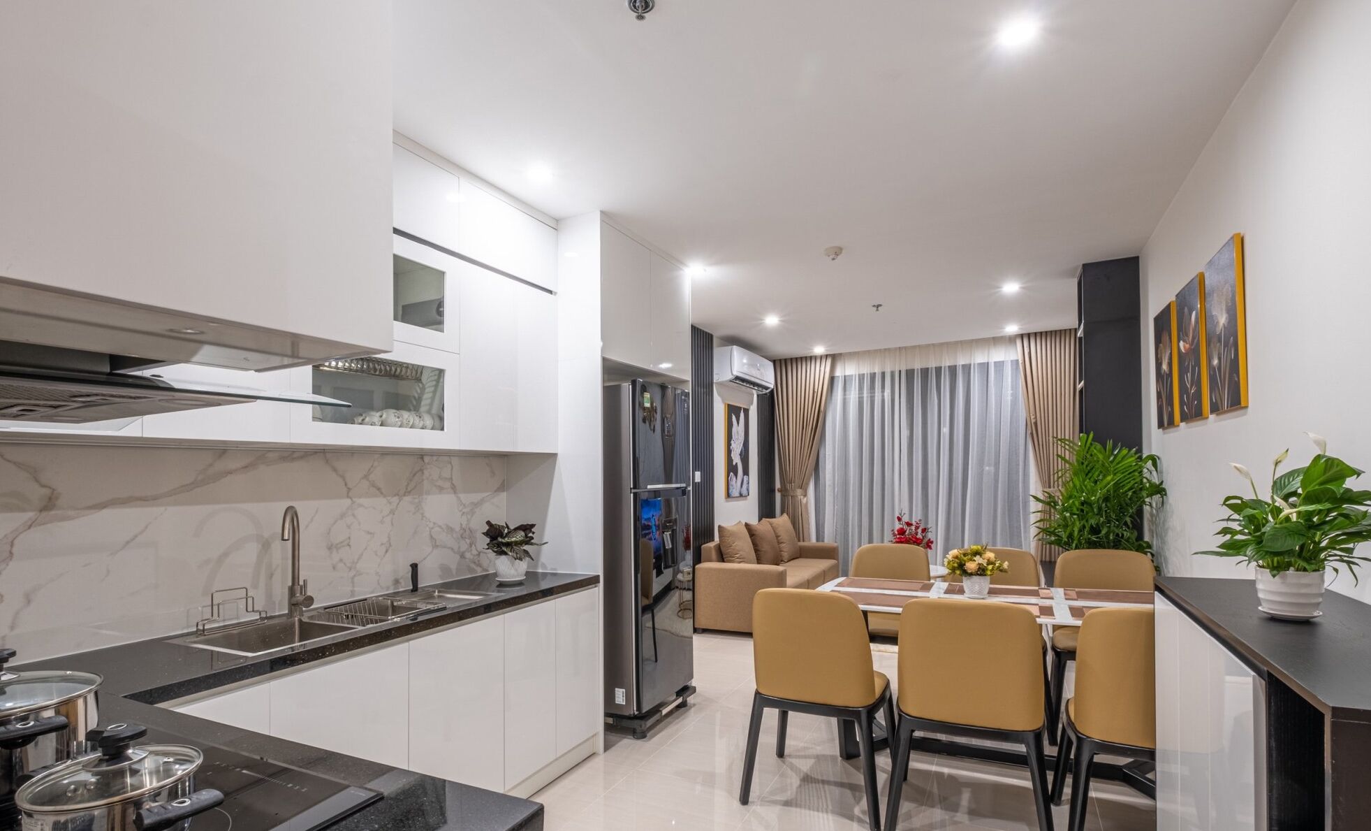 Una cocina moderna con encimera de mármol, electrodomésticos de acero inoxidable y un comedor con mesa y sillas.