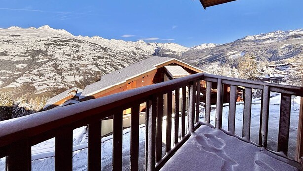 Eine Holztreppe führt zu einem Raum mit Blick auf schneebedeckte Berge.