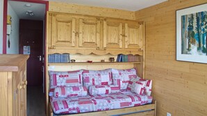 Ein gemütliches Zimmer mit einem hölzernen Etagenbett, einem Schrank darüber und einem gerahmten Gemälde an der Wand.