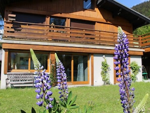A modern building with a wooden balcony, large windows, and a well-maintained lawn.