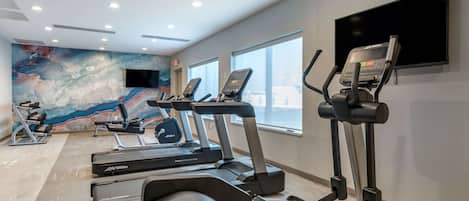 A gym with treadmills, elliptical machines, and a stationary bike.
