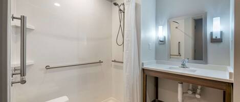A modern bathroom with a walk-in shower, a white toilet, a sink with a mirror, and a towel rack.