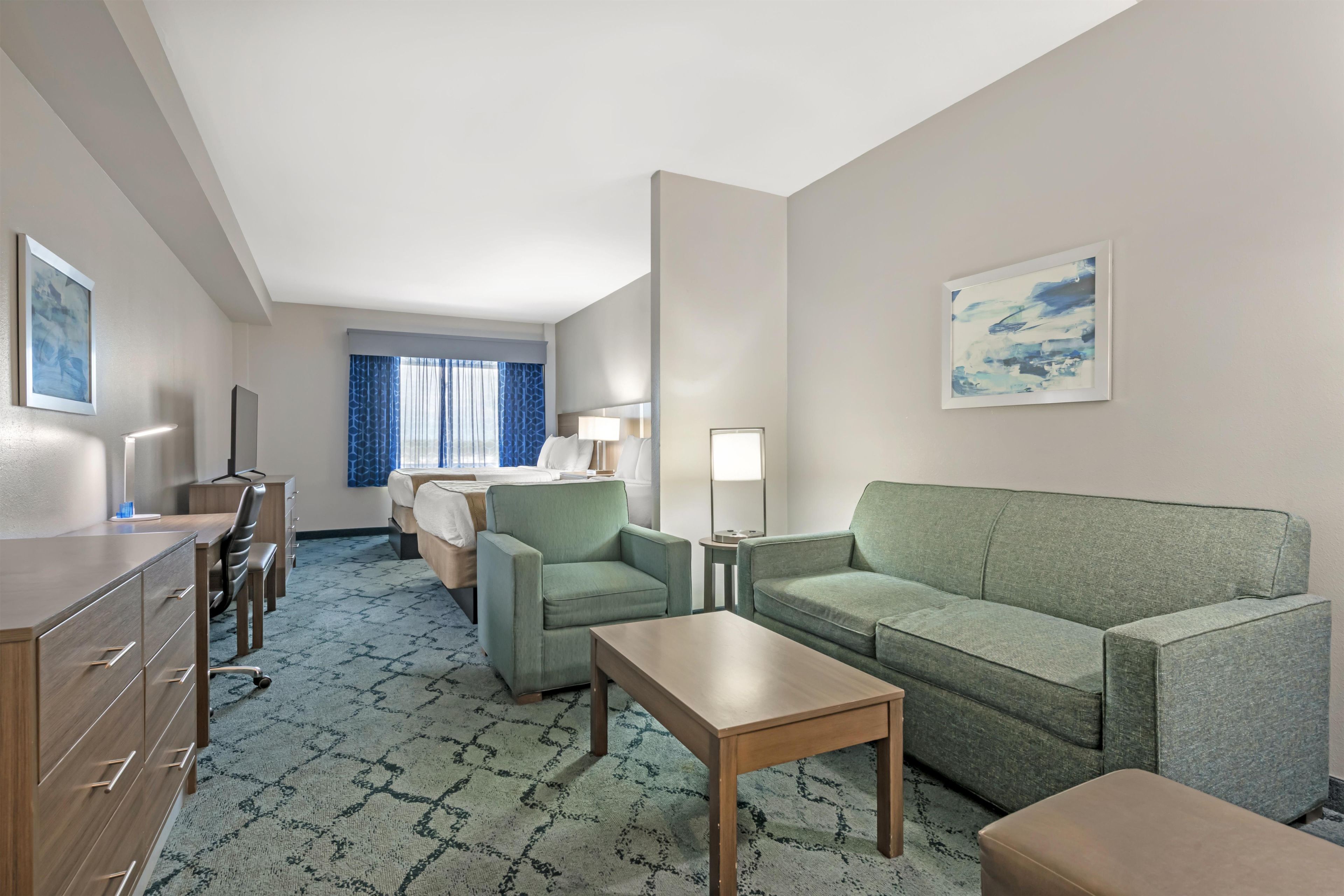 Une chambre d’hôtel comprenant un lit, un bureau, une chaise, un canapé et une petite table.