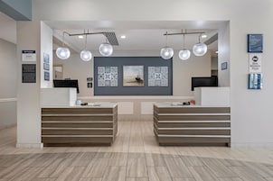 A reception area with two reception desks, a large wall-mounted TV, and decorative tiles.