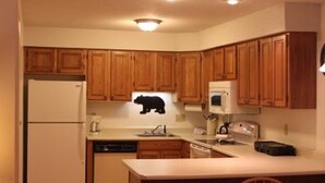 Eine kleine Küche mit Holzausstattung, einem Kühlschrank, einer Mikrowelle und einem Spülbecken.