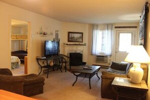 Cozy living room with a fireplace, television, and comfortable seating area featuring a sofa and armchairs.