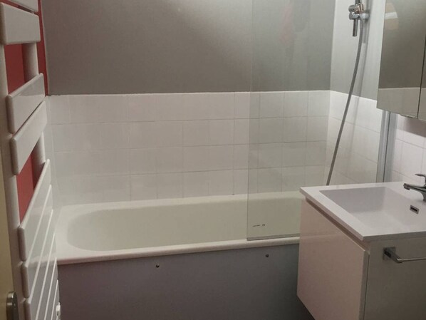 Un bany amb una banyera blanca, un lavabo i una dutxera.