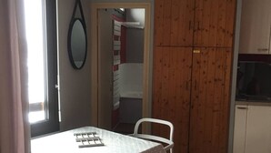 Una cocina pequeña con una puerta de madera, una mesa blanca con mantel estampado de lunares y una silla blanca.