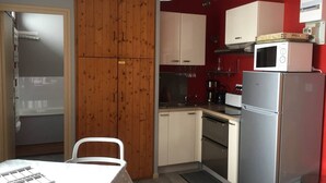 Una cocina compacta con muebles de madera, un refrigerador blanco, un microondas y una cafetera.
