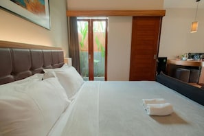 Habitación de hotel con una cama grande, cabecera de madera, escritorio con una silla y vistas a través de un ventanal.