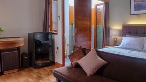 A hotel room with a bed, a sofa, a desk, and a sliding door leading to a bathroom. - Andewi Guest House Denpasar (Denpasar)