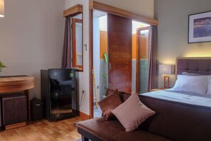 Una habitación de hotel con cama, sofá, escritorio y puerta corredera que da al baño.
