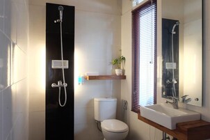 Uma casa de banho moderna com sanita, chuveiro, lavatório e espelho.