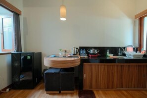 Cocina compacta con una isla redonda de madera, un refrigerador negro y un ventanal que proporciona luz natural.