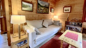 A cozy room with a white sofa, wooden walls, and framed pictures on the wall.