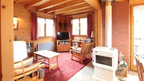 A cozy cabin interior with wooden walls, a TV, a fireplace, and a dining area.