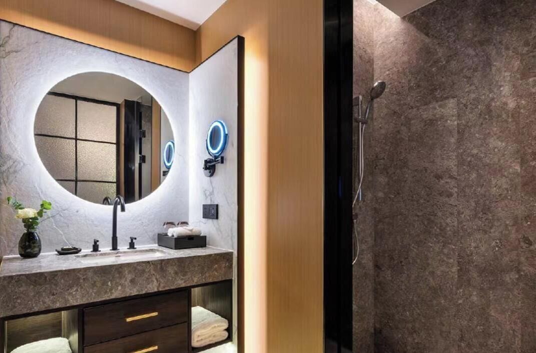Une salle de bain moderne avec un meuble-lavabo en marbre, un grand miroir, une douche avec une porte en verre et un porte-serviettes.