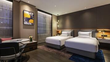 A modern hotel room with two beds, a desk, and a chair.