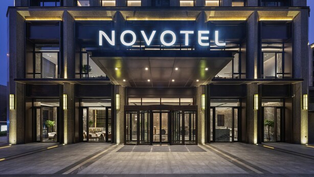 A hotel entrance with a 'NOVOTEL' sign, glass doors, and a covered entrance area. - Novotel Tianjin Drum Tower (Tianjin)