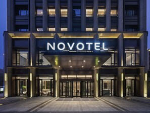A hotel entrance with a 'NOVOTEL' sign, glass doors, and a covered entrance area. - Novotel Tianjin Drum Tower (Tianjin)