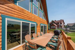 A wooden cabin with a deck, outdoor seating, and large windows. - Lakefront Lodge w/ Hot Tubs, Games & More (Swanton)